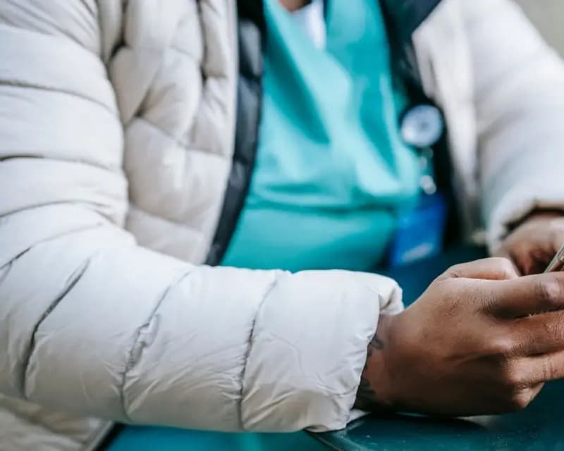 A nurse in teal scrubs holding a phone